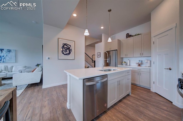 kitchen featuring sink, hardwood / wood-style flooring, hanging light fixtures, an island with sink, and stainless steel appliances