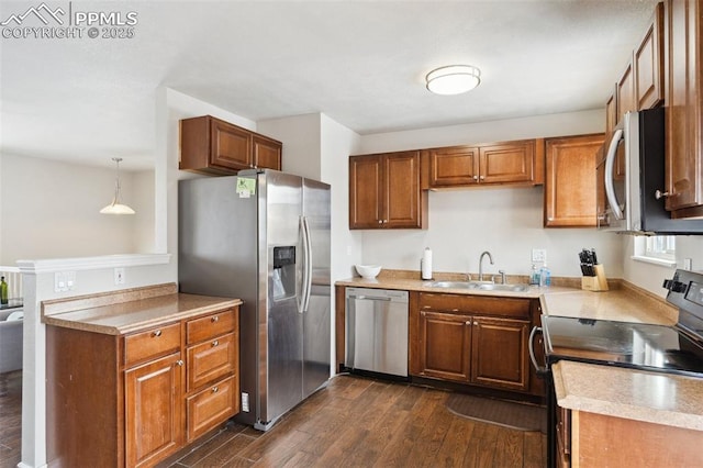 kitchen with sink, dark hardwood / wood-style floors, hanging light fixtures, and appliances with stainless steel finishes