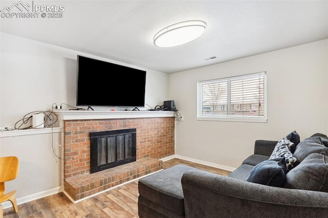 living room with a brick fireplace and hardwood / wood-style floors