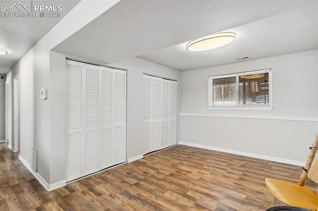 unfurnished bedroom with multiple closets and hardwood / wood-style floors