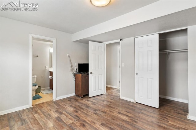 unfurnished bedroom with ensuite bathroom and dark hardwood / wood-style floors