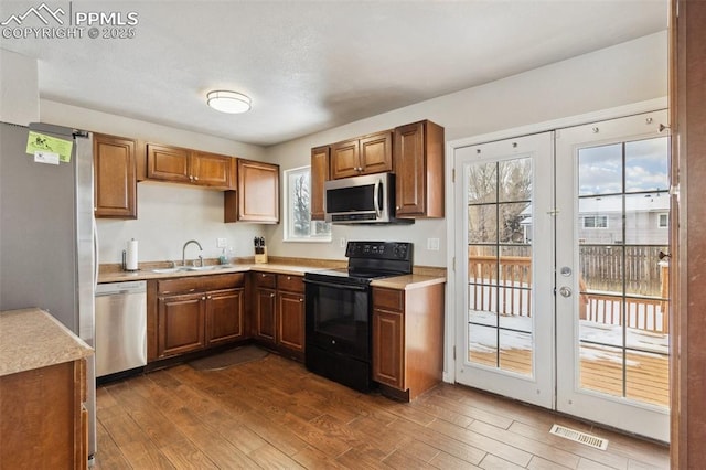 kitchen with sink, appliances with stainless steel finishes, dark hardwood / wood-style floors, and french doors