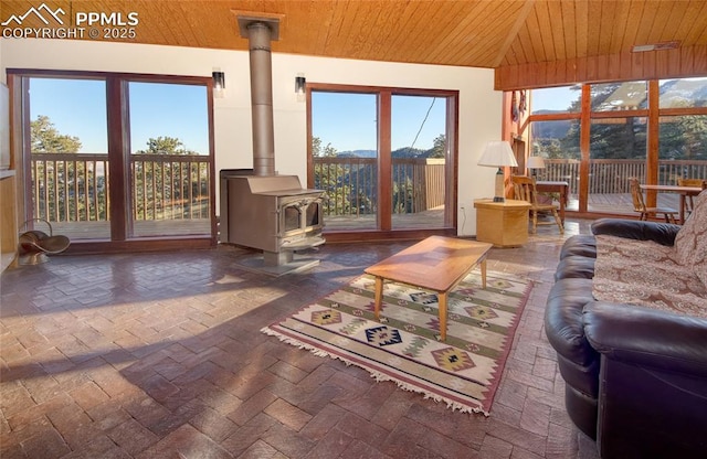 sunroom / solarium featuring a wood stove and wooden ceiling