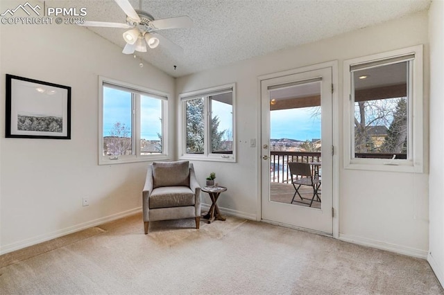 living area with ceiling fan, lofted ceiling, light carpet, and a textured ceiling