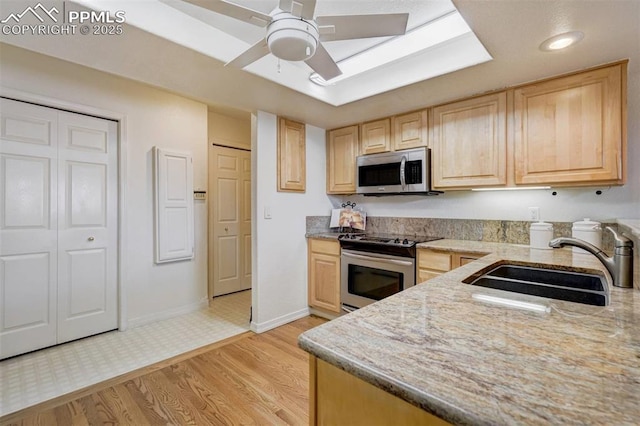 kitchen featuring appliances with stainless steel finishes, sink, light brown cabinets, and light hardwood / wood-style flooring