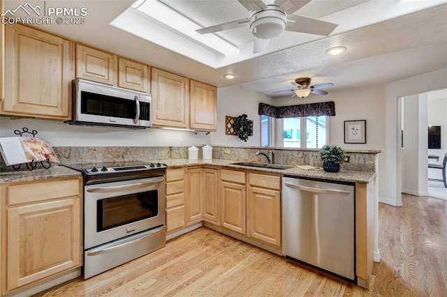 kitchen with sink, stainless steel appliances, light hardwood / wood-style floors, light brown cabinetry, and kitchen peninsula