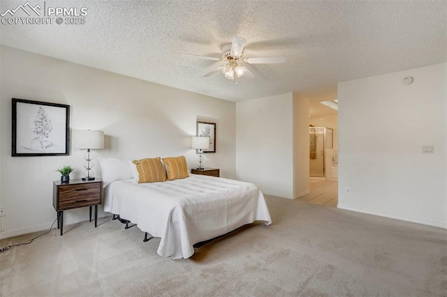 bedroom with ceiling fan, connected bathroom, light carpet, and a textured ceiling