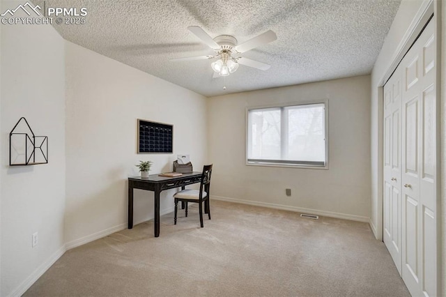 carpeted home office with a textured ceiling and ceiling fan