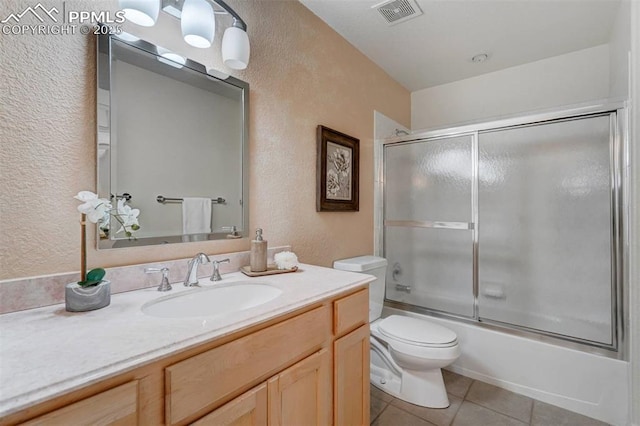 full bathroom with tile patterned flooring, vanity, shower / bath combination with glass door, and toilet