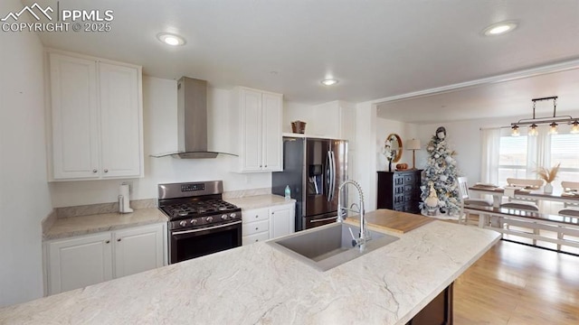 kitchen with sink, white cabinets, wall chimney exhaust hood, and stainless steel appliances