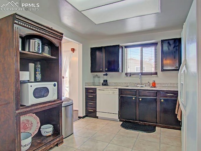 kitchen featuring light tile patterned floors, dark brown cabinets, sink, and white appliances