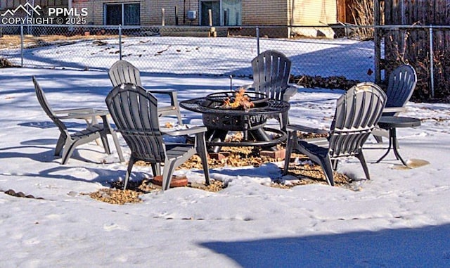 snow covered patio with an outdoor fire pit