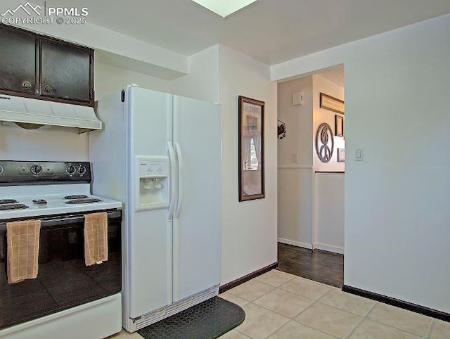 kitchen featuring light tile patterned flooring, dark brown cabinets, and white appliances