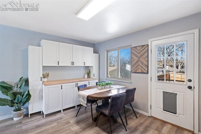 kitchen with white cabinets, light hardwood / wood-style floors, and butcher block countertops