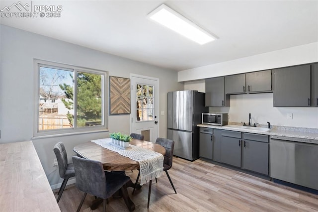 kitchen featuring sink, appliances with stainless steel finishes, gray cabinets, and light wood-type flooring