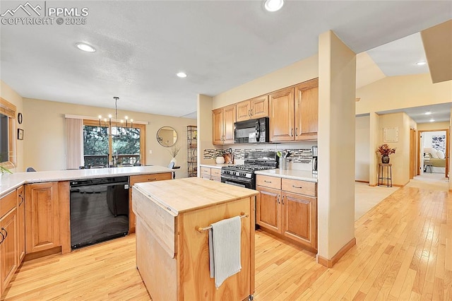 kitchen featuring wooden counters, backsplash, hanging light fixtures, a kitchen island, and black appliances