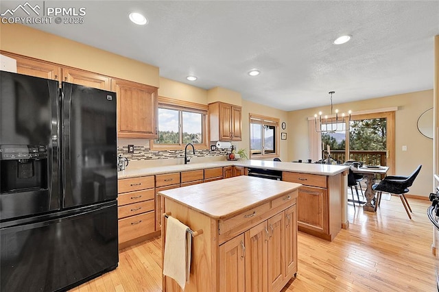 kitchen featuring decorative light fixtures, decorative backsplash, a center island, and black appliances