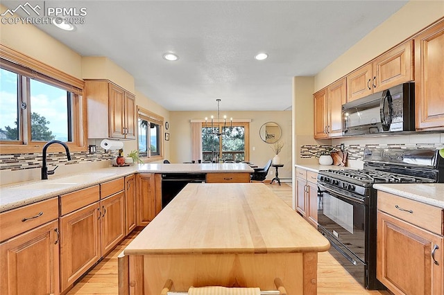 kitchen with black appliances, butcher block countertops, decorative light fixtures, and a center island