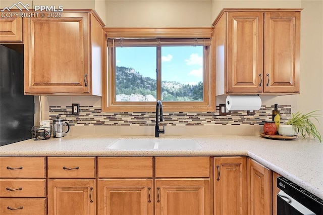 kitchen featuring dishwasher, backsplash, light stone counters, and sink