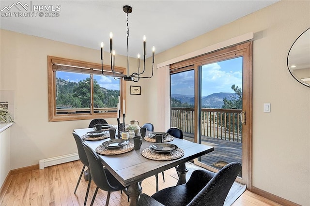 dining area with a mountain view, baseboard heating, a notable chandelier, and light hardwood / wood-style floors