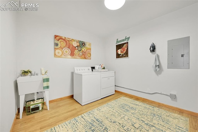 laundry room with electric panel, independent washer and dryer, and wood-type flooring