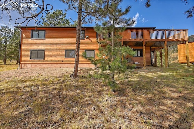 back of property featuring a wooden deck and a lawn