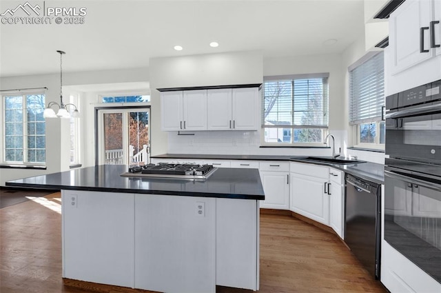 kitchen with white cabinetry, sink, black appliances, and a center island