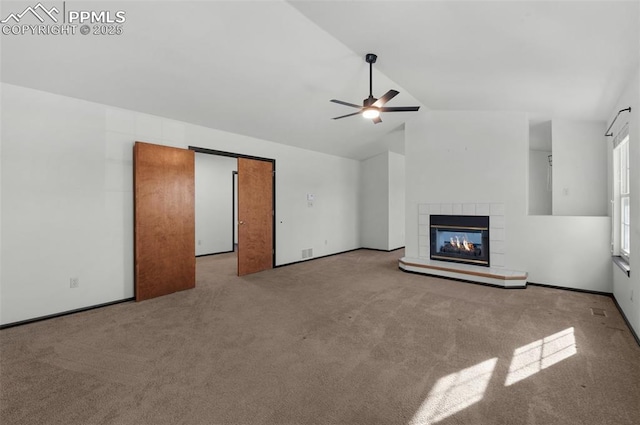 unfurnished living room with lofted ceiling, a fireplace, light colored carpet, and ceiling fan