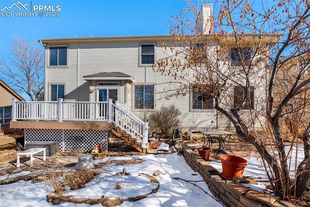 snow covered rear of property with a wooden deck