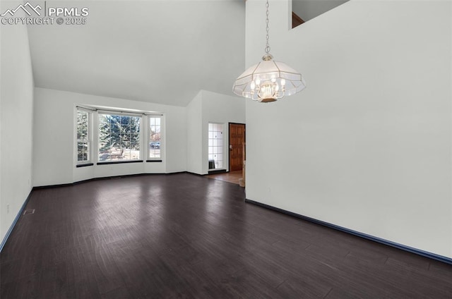 unfurnished room featuring an inviting chandelier, dark hardwood / wood-style floors, and a high ceiling