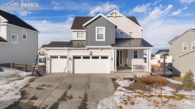 view of front of home featuring a standing seam roof, covered porch, fence, concrete driveway, and board and batten siding