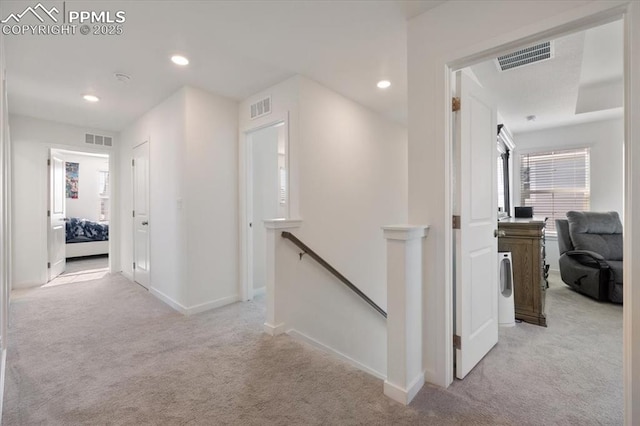 corridor with light carpet, visible vents, and an upstairs landing