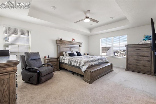 bedroom featuring baseboards, ceiling fan, a raised ceiling, and light colored carpet