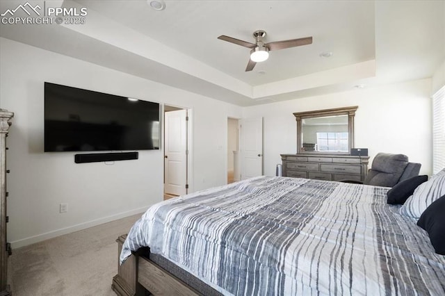 bedroom featuring a ceiling fan, baseboards, a tray ceiling, and carpet flooring