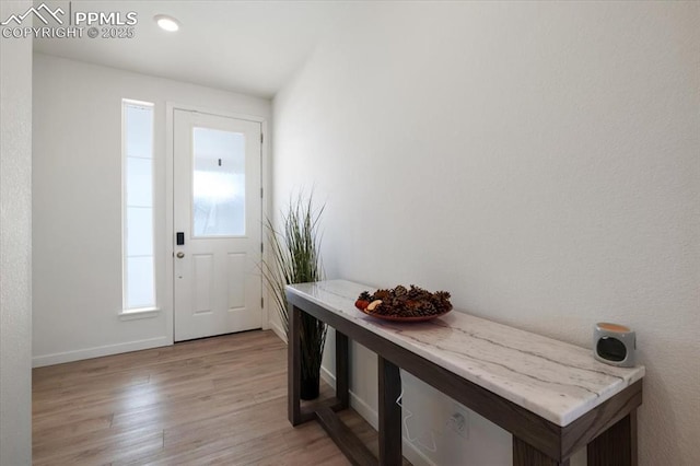 doorway featuring light wood-style flooring and baseboards