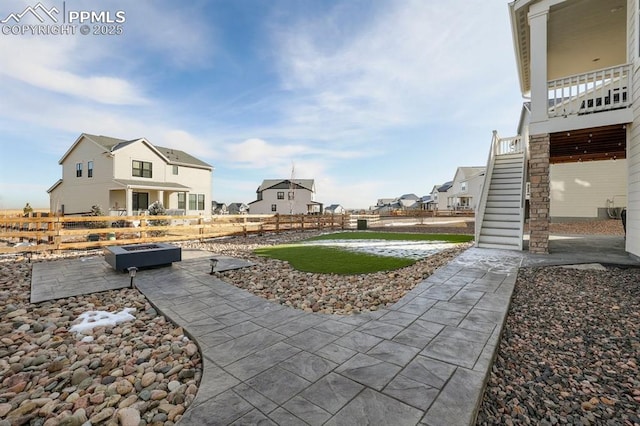 view of yard featuring a patio area, fence, stairway, and a residential view