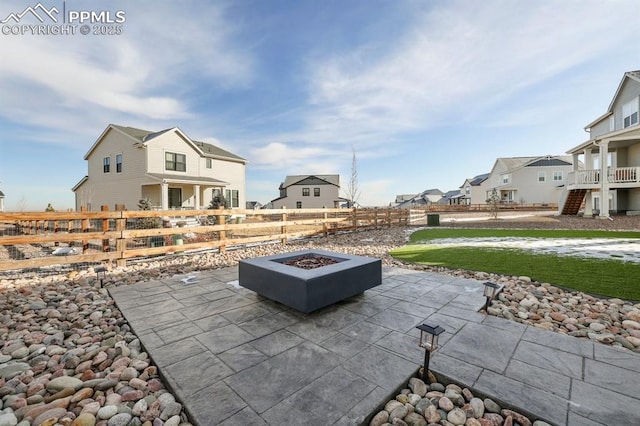 view of patio featuring fence, a fire pit, and a residential view