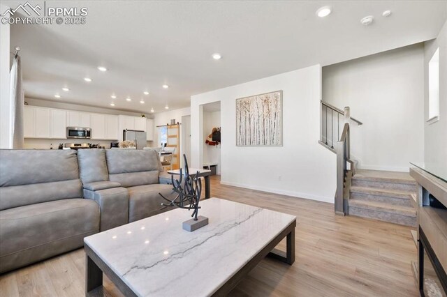 living room with stairs, light wood-type flooring, and recessed lighting