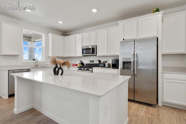 kitchen with appliances with stainless steel finishes, white cabinetry, a sink, and light wood-style flooring