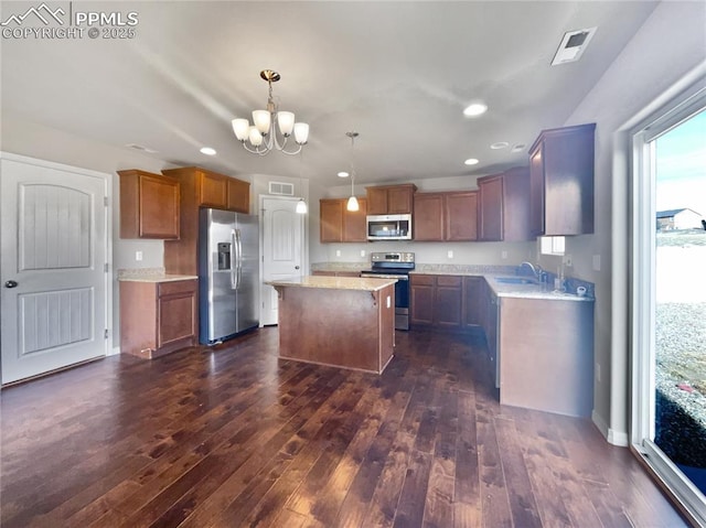 kitchen with stainless steel appliances, a notable chandelier, decorative light fixtures, dark hardwood / wood-style flooring, and a center island