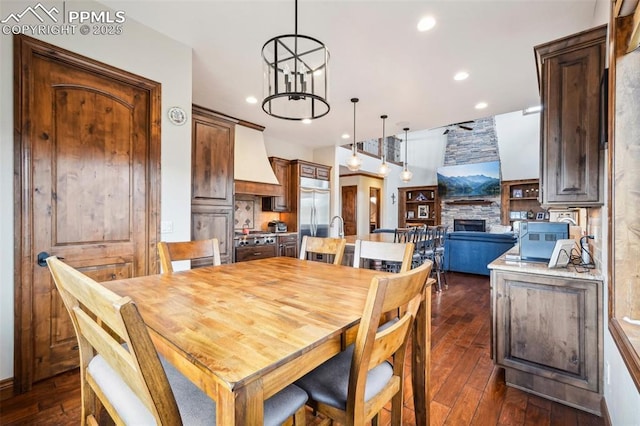 dining area featuring dark hardwood / wood-style flooring, a notable chandelier, and a fireplace