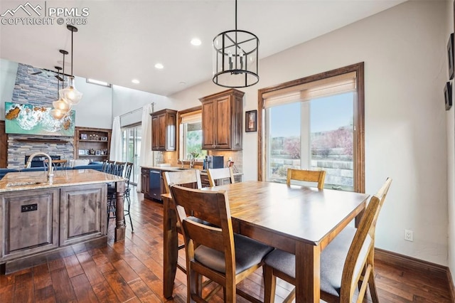 dining space featuring dark hardwood / wood-style floors, sink, and a stone fireplace