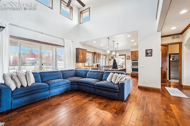 living room with dark wood-type flooring, a high ceiling, and ceiling fan