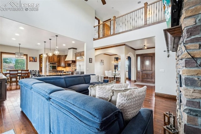 living room featuring ceiling fan, dark wood-type flooring, and a towering ceiling