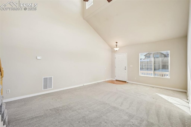 interior space with ceiling fan, light carpet, and a towering ceiling