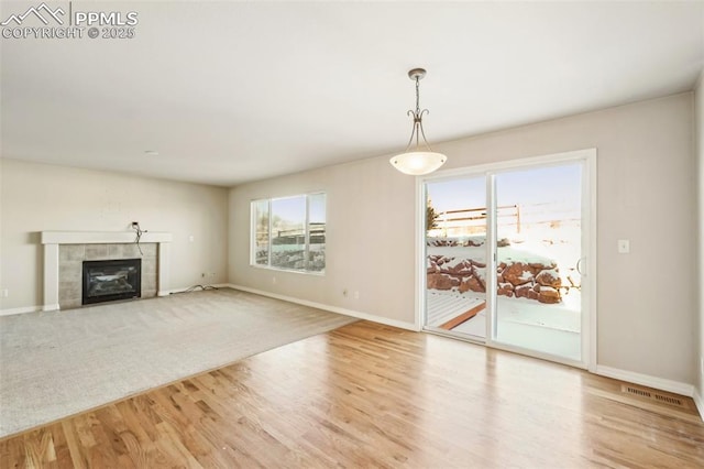 unfurnished living room with light hardwood / wood-style flooring, plenty of natural light, and a tile fireplace