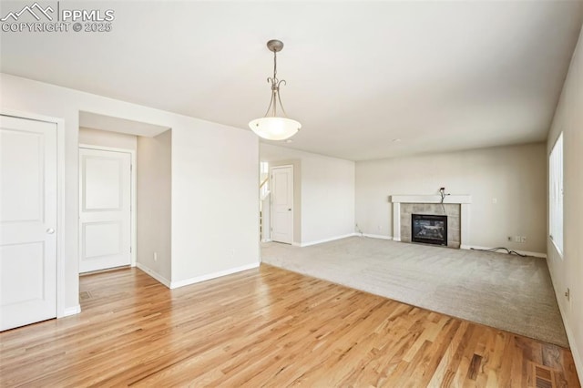 unfurnished living room featuring light hardwood / wood-style flooring and a tiled fireplace