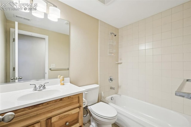 full bathroom featuring toilet, tiled shower / bath, and vanity