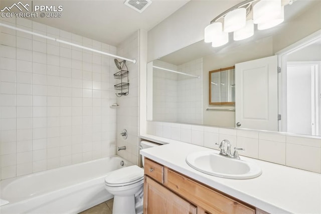 full bathroom with toilet, tiled shower / bath, backsplash, tile patterned floors, and vanity