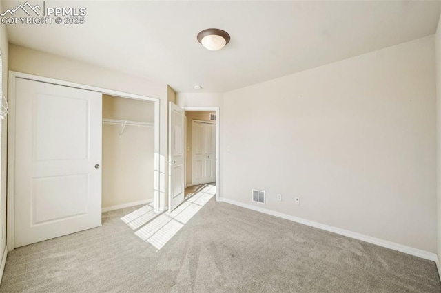 unfurnished bedroom with light colored carpet and a closet